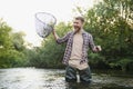 Fisherman picking up big rainbow trout from his fishing net