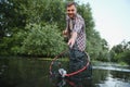 Fisherman picking up big rainbow trout from his fishing net