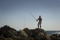 Fisherman on a pier, rock fishing session. Alicante, Spain