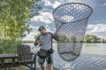 Fisherman with pike fish in fishing landing net Royalty Free Stock Photo