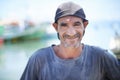 Fisherman, portrait and rugged man with smile, harbour and wrinkles from sunlight exposure. Boats, ships and water or Royalty Free Stock Photo