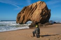 Fisherman in Praia de Santa Cruz beach rock boulder, Portugal