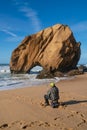 Fisherman in Praia de Santa Cruz beach rock boulder, Portugal