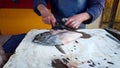 Fisherman prepares reine fish defin, skin and decapitate