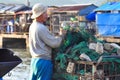 A fisherman is preparing his fishing net for a new working day at a local seaport Royalty Free Stock Photo