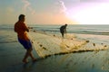 A fisherman is pulling up a net nearby a beach Royalty Free Stock Photo