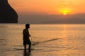 A fisherman pulls in his net at sunset on Rajamangala beach in Trang province, Thailand