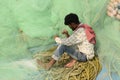 Fisherman repairing fishing net for his trawler for the voyage at Frezarganj fish harbor, west Bengal, india