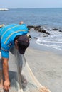 Fisherman repairing a net used for fishing on a Colombian beach