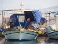 Fisherman repairing nets on a fishing boat on a sunny afternoon on the calm Aegean Sea on the island of Evia, Greece