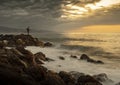 Fisherman on rocks fishing in front of the Mediterranean sea in an orange sunrise