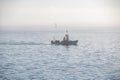 FishermanÃ¢â¬â¢s boat going across the ocean on a foggy day Royalty Free Stock Photo