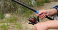 Fisherman`s fishing rod with inertia-free coil in summer on shore of lake close up