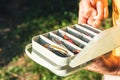 The fisherman`s hands are holding a plastic box with a variety of lures and fishing hooks Royalty Free Stock Photo