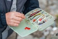 The fisherman's hands are holding a plastic box with a variety of lures and fishing hooks Royalty Free Stock Photo