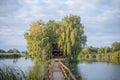 Fisherman`s house with a wooden pedestrian bridge on a tiny island in the middle of the lake. Autumn view. Old Solotvyn village. Royalty Free Stock Photo