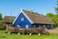 Fisherman`s museum. Beautiful old Lithuanian traditional wooden blue houses with thatched roof and old boat Royalty Free Stock Photo