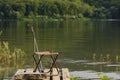 Fisherman`s place. A chair, a fishing rod and fish bait rests on a stone against the backdrop of a large river Royalty Free Stock Photo