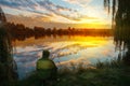 Fisherman seated by lake at sunset under dramatic sky Royalty Free Stock Photo