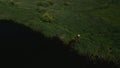 A fisherman on the shore of the lake catches fish on a spinning rod. Aerial photography