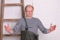 Fisherman shows hands the size of fish on white wall background.