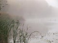 Fisherman silhouette on a boat on a misty morning lake