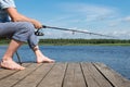 Fisherman sits on a chair and catches fish from the pier on the bait