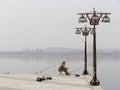 Fisherman sits on municipal embankment and fishes