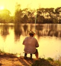 Fisherman sitting at beach sunset and fishing