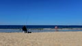 Fisherman Sitting on a Bucket On a Beach with American Flag Nearby with Copy Space