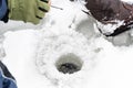 Fisherman sitting on frozen water near drilled hole in ice. Winter fishing concept Royalty Free Stock Photo