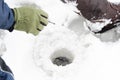 Fisherman sitting on frozen water near drilled hole in ice. Winter fishing concept Royalty Free Stock Photo