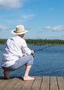 A fisherman is sitting on a pier with a fishing rod waiting for a big fish to bite Royalty Free Stock Photo