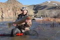 Fisherman sitting in river holding a steelhead trout