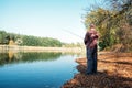 Fisherman with spinning rod on the autumn lake. fisherman with spinning in his hands catching fish at sun day. Fisherman Royalty Free Stock Photo