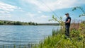 Fisherman with spinning rod on nature background. Angler man with fishing spinning or casting rod by the river