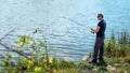 Fisherman with spinning rod on nature background. Angler man with fishing spinning or casting rod by the river