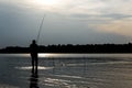 Fisherman standing knee-deep in the water at sunset in the river fishing Royalty Free Stock Photo