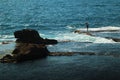Fisherman standing on a rock on the beach Royalty Free Stock Photo