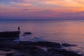 The fisherman standing on the rock with sunset background. Royalty Free Stock Photo