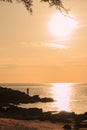 Fisherman standing on rock under sunset light Royalty Free Stock Photo