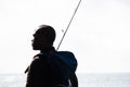Fisherman standing by sea with fishing rod