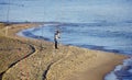 Fisherman standing at the seashore hooks a fish. Sportsman holds a fishing rod and reel in a hooked fish. Spin Fishing hobby