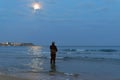 Fisherman standing at the seashore hooks a fish. Sportsman holds a fishing rod and reel in a hooked fish. Spin Fishing