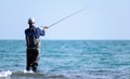 Fisherman standing at the seashore hooks a fish. Sportsman holds a fishing rod and reel in a hooked fish. Spin Fishing hobby