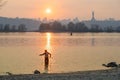 Fisherman stands in the river Dnipro. Sunset over Kyiv and the Motherland Monument. Ukraine.