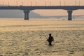 Fisherman stands in the river Dnipro. Sunset over Kyiv and the Motherland Monument. Ukraine.