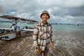 fisherman stands with a small boat resting on the beach