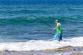 A fisherman stands in the water and fishes with a fishing rod on the Mediterranean coast near the Nahariya city in Israel