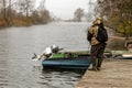 A fisherman stands on a wooden pier and holds a fishing rod. Mist over the water. Autumn landscape. The fisherman does not give up Royalty Free Stock Photo